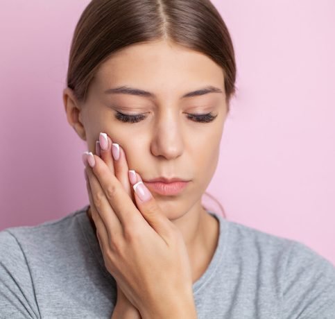 Portrait of a beautiful young woman experiencing a painful toothache.